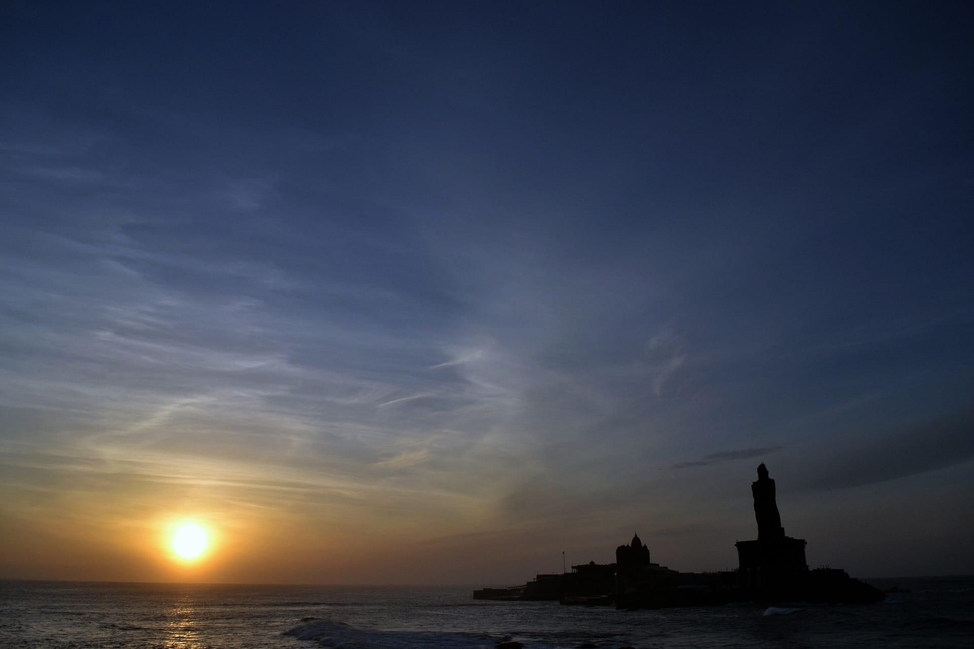 Sunrise over the sea at Kanyakumari, with the Vivekananda Rock Memorial in silhouette