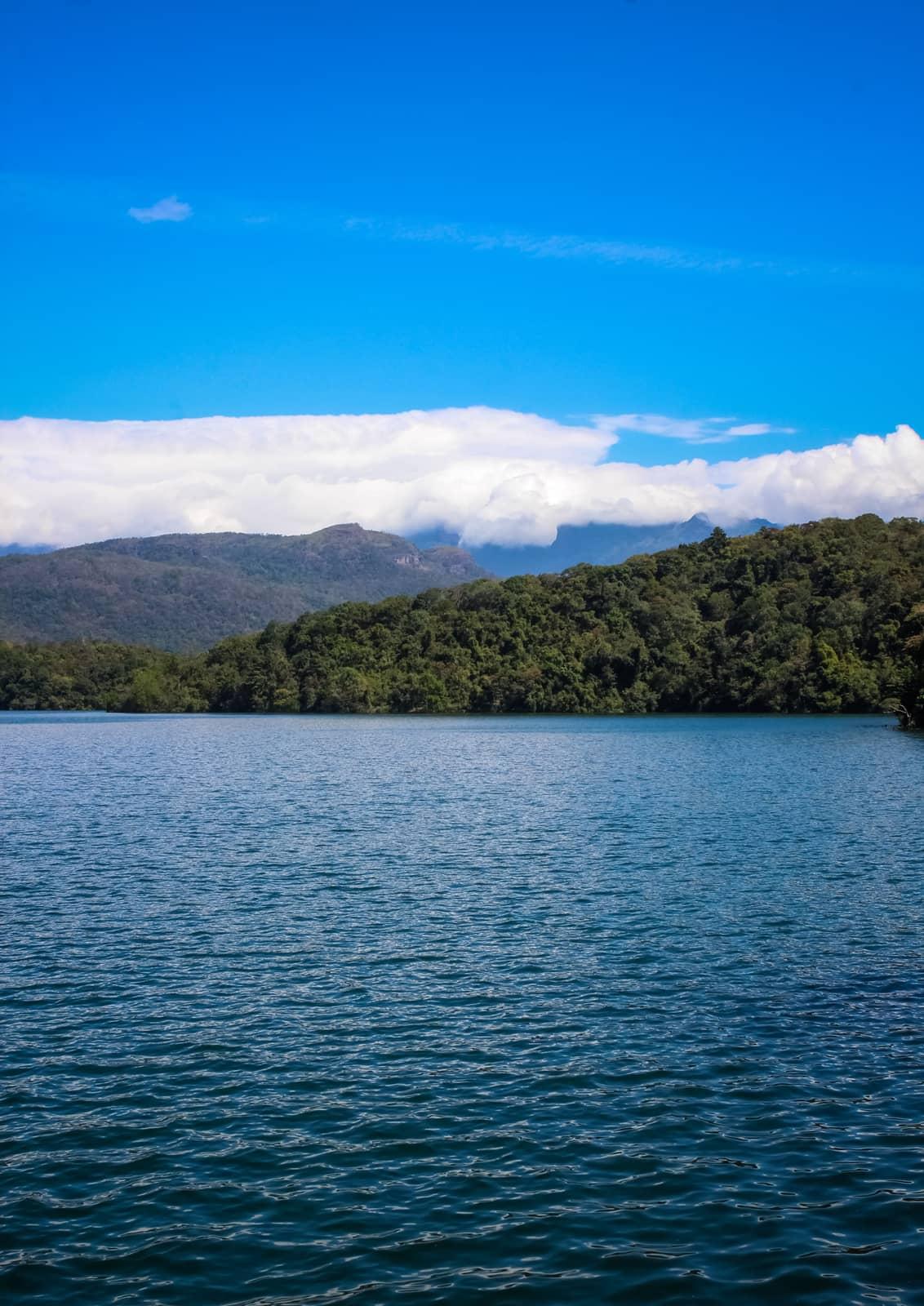 The blue reservoir of Neyyar Dam with forested hills behind, near Thiruvananthapuram