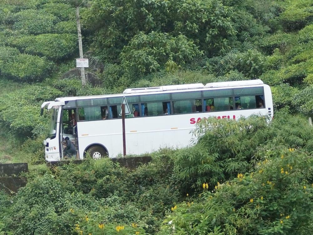 A white tourist bus on a hill road through the tea estates near Munnar