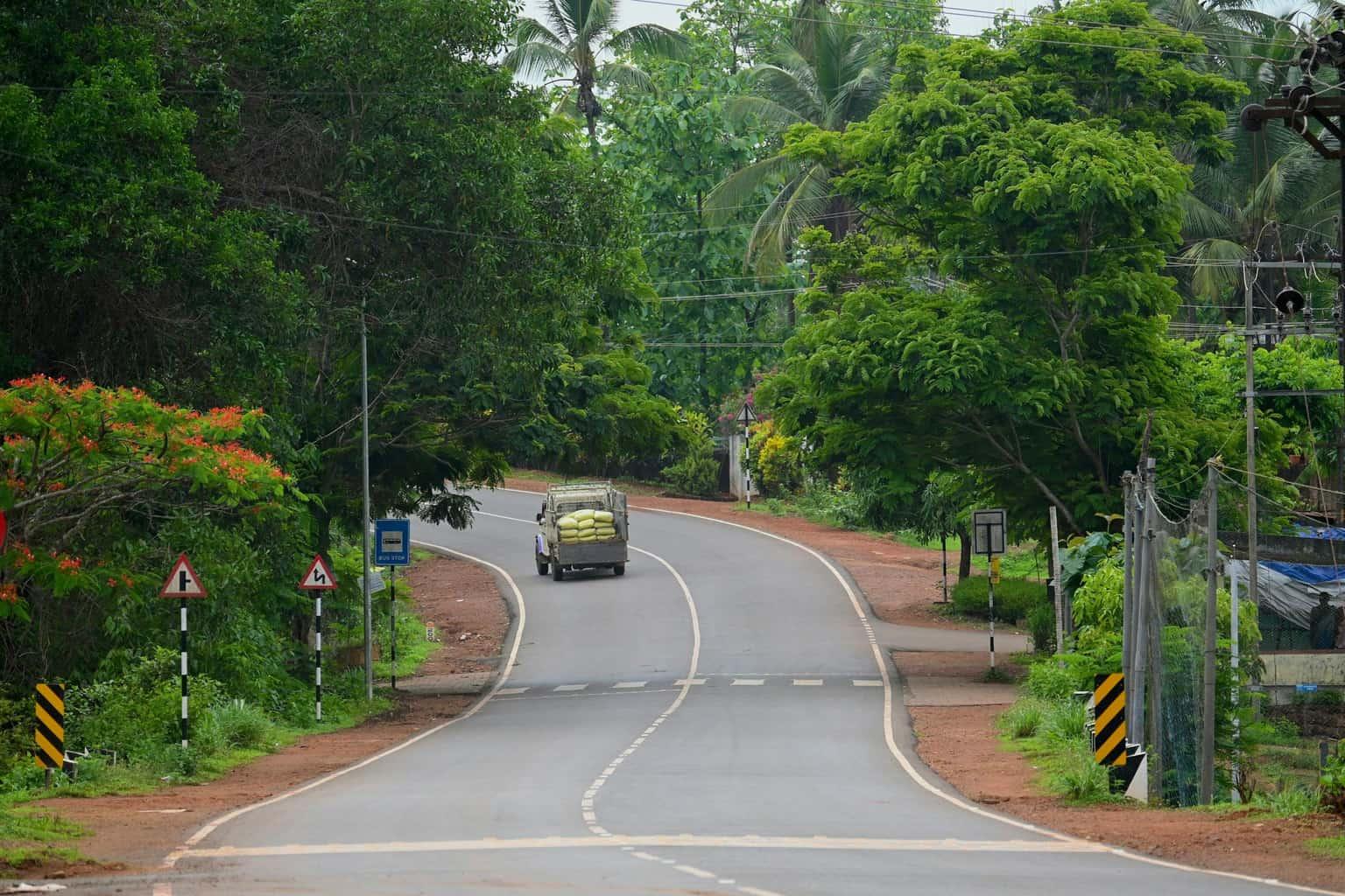 A car on a winding road through green hills in Kasaragod, Kerala